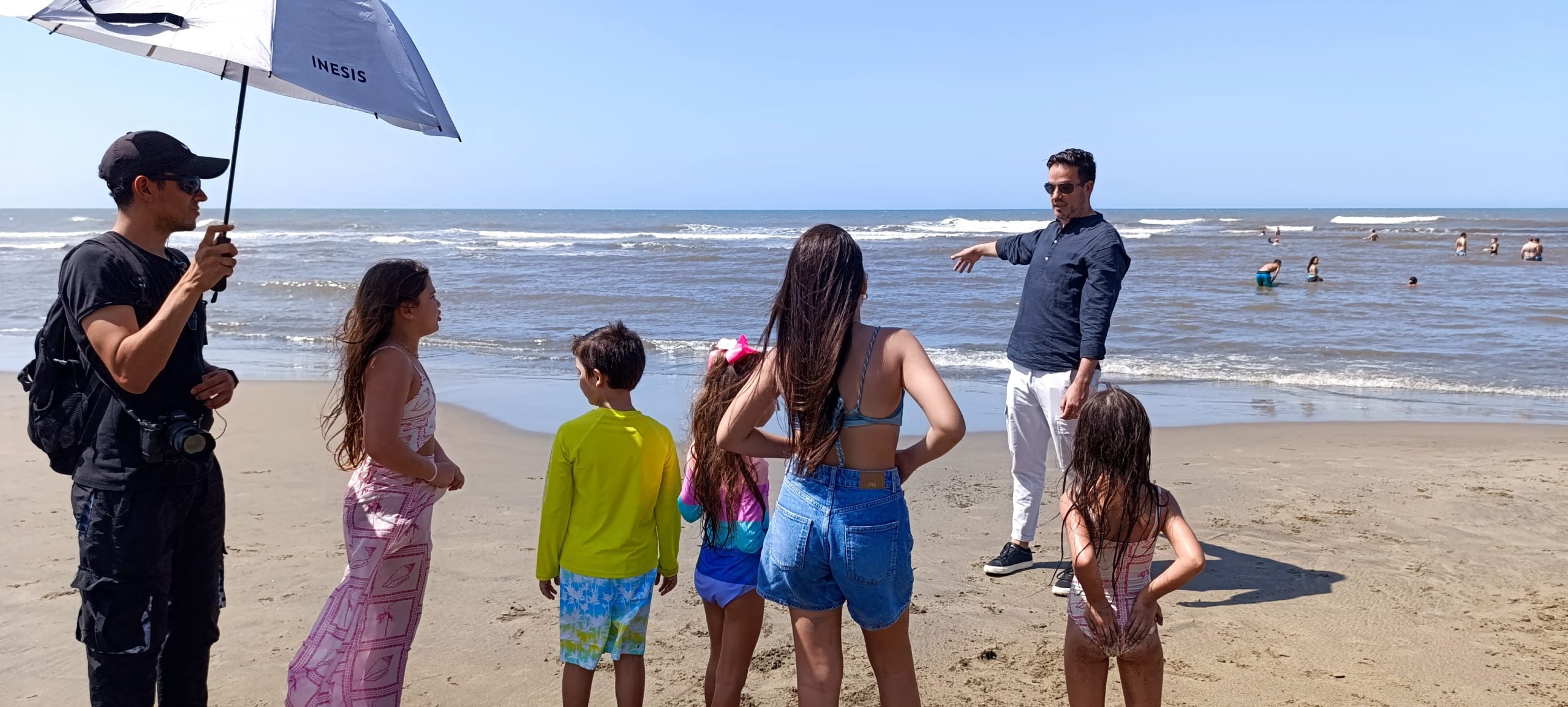 Equipo la7em dando indicaciones a niños para grabación en la playa