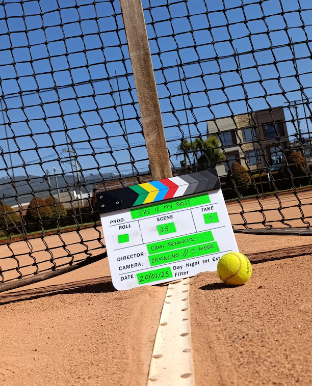 Claqueta de she is my boss en una cancha de tenis